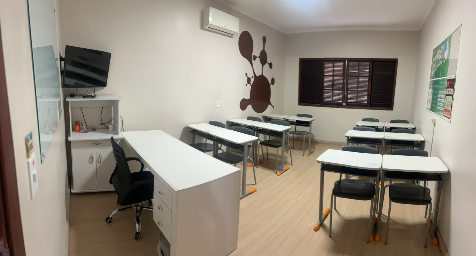 Sala de treinamentos com carteiras para até 12 pessoas, TV e mesa de instrutor